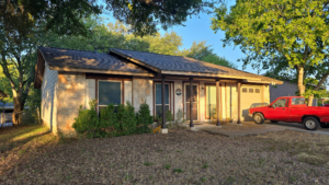 Outside view of a tan color home with a newly installed brown roof by Dolan Roofing & Construction in San Antonio, TX